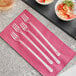A group of Visions clear plastic forks on a pink napkin.
