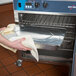 A person using an Alto-Shaam undercounter cook and hold oven in a professional kitchen.