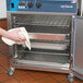 A person cleaning an Alto-Shaam undercounter cook and hold oven with a towel.