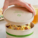 A hand holding a World Centric compostable container of food.