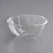 A clear plastic World Centric deli bowl on a gray surface.