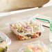 A World Centric clear compostable plastic hinged clamshell container of pasta and vegetables on a table.