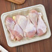 A World Centric compostable fiber meat tray holding raw chicken legs.