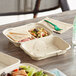 A World Centric compostable hoagie box with a sandwich inside on a table.