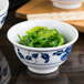 A white melamine rice bowl filled with green seaweed.