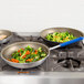 Two Vollrath aluminum non-stick fry pans with vegetables on a stove.