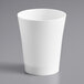 A Choice white plastic shot glass on a gray surface.
