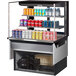 A Turbo Air black drop-in refrigerated display case with cans of soda and water on shelves.