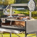 A Nuke BBQ Puma charcoal grill on a table with meat cooking on the grill.