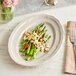 An Acopa Warm Gray porcelain platter with asparagus and almonds on it.