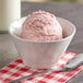 A bowl of pink strawberry ice cream with a spoon.