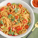 A bowl of spaghetti with tomatoes and cilantro topped with McCormick Culinary Sriracha Seasoning.