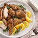 A plate of food with lemons, chicken, and McCormick Herbes de Provence.