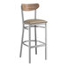 A Lancaster Table & Seating bar stool with a wooden seat and metal back.