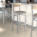 Lancaster Table & Seating bar stools with a driftwood back and dark gray vinyl seats at a counter.