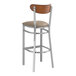 A Lancaster Table & Seating bar stool with a taupe vinyl seat and wooden back.