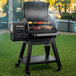 A Louisiana Grills Black Label 800 pellet grill on a table with meat and vegetables cooking on it.