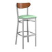 A Lancaster Table & Seating bar stool with a seafoam vinyl seat and wood back.