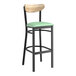 A Lancaster Table & Seating bar stool with a seafoam green vinyl seat and black frame.