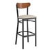A black Lancaster Table & Seating bar stool with a light gray seat.