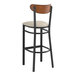 A Lancaster Table & Seating bar stool with a black finish, light gray cushion, and wood back.