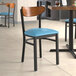 A Lancaster Table & Seating Boomerang chair with a blue vinyl seat at a restaurant table.