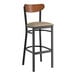 A Lancaster Table & Seating black bar stool with taupe vinyl seat and a wooden back.