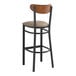 A Lancaster Table & Seating black bar stool with taupe cushion and wood back.