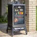 A Louisiana Grills vertical smoker with meat and vegetables inside.