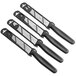 A group of four Mercer Culinary paring knives with black handles.