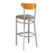 A Lancaster Table & Seating Boomerang bar stool with dark gray vinyl seat and cherry wood back.
