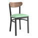 A Lancaster Table & Seating Boomerang Series chair with a green seat cushion and black and vintage wood finish.