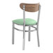 A Lancaster Table & Seating metal chair with a seafoam vinyl seat and vintage wood back.