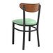 A Lancaster Table & Seating black chair with green vinyl seat and antique walnut wood back.