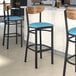 A Lancaster Table & Seating bar stool with blue vinyl seat and vintage wood back, black finish.