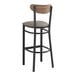 A Lancaster Table & Seating Boomerang series bar stool with a metal and wood vintage back, dark gray cushion, and black finish.