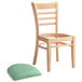 A Lancaster Table & Seating wood restaurant chair with a detached green vinyl cushion seat.