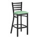 A Lancaster Table & Seating black ladder back bar stool with a seafoam green vinyl padded seat.
