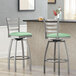 Two Lancaster Table & Seating ladder back swivel bar stools with seafoam green vinyl padded seats at a counter.