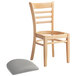 A Lancaster Table & Seating wooden restaurant chair with a light gray cushion.