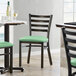 A Lancaster Table & Seating black metal ladder back chair with a 2 1/2" seafoam vinyl padded seat.