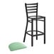 A Lancaster Table & Seating black ladder back bar stool with a seafoam green padded seat.
