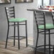 A Lancaster Table & Seating black ladder back bar stool with a seafoam vinyl padded seat.