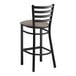 A Lancaster Table & Seating black ladder back bar stool with a dark gray vinyl padded seat.