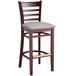 A Lancaster Table & Seating mahogany wood bar stool with a light gray cushion on the seat.