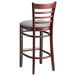A Lancaster Table & Seating mahogany wood bar stool with a light gray vinyl seat and ladder back.