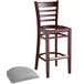 A Lancaster Table & Seating mahogany wood ladder back bar stool with a light gray vinyl seat