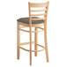 A Lancaster Table & Seating wooden ladder back bar stool with a taupe cushion on the seat.