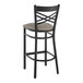 A Lancaster Table & Seating black cross back bar stool with a dark gray vinyl padded seat.