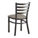 A black metal Lancaster Table & Seating ladder back chair with a dark gray vinyl cushion